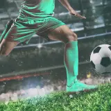 Piłkarz w akcji, gotowy do strzału. W tle stadion, gdzie rodzą się legendy piłki nożnej.