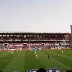 Mecz na madryckim stadionie. Piłkarze biegają po zielonej murawie, a trybuny wypełniają kibice.