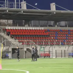 Piłkarze Polonii Bytom trenują na nowym stadionie. Puste trybuny z czerwonymi i niebieskimi krzesełkami czekają na kibiców.