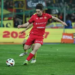 GKS Katowice piłkarze w akcji. Zawodnik w czerwonej koszulce drybluje z piłką na boisku, walcząc o zwycięstwo.