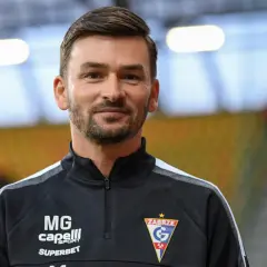 Uśmiechnięty trener Górnika Zabrze w czarnej bluzie z logo klubu.