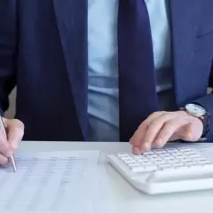 Biznesmen liczy zyski, analizując dokumenty i kalkulując podatek od zakładów bukmacherskich.