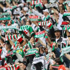 Tłum kibiców Legii Warszawa z szalikami, na których widnieje tekst "Legia Warszawa" i "Legia".