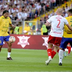 Ronaldinho w żółtej koszulce z numerem 10 drybluje piłką na boisku, gdzie grał.