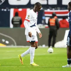Piłkarz PSG, Ousmane Dembélé, schodzi z boiska, prawdopodobnie z powodu kontuzji. Obok niego inni zawodnicy.