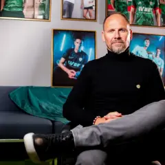 Trener Śląska Wrocław, Ivan Djurdjević, siedzi na kanapie w otoczeniu zdjęć piłkarzy.