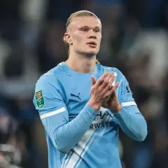 Erling Haaland w błękitnej koszulce Manchesteru City, z pucharem Carabao Cup na rękawie, klaszcze.