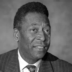 Portret czarno-biały. Uśmiechnięty mężczyzna w garniturze. Czy Pele żyje? Tak, legenda futbolu wciąż inspiruje.