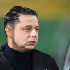 Borysiuk, piłkarz, w czarnym golfie i kurtce, z uwagą obserwuje grę.