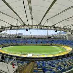 Pusta Marakana, stadion w Rio de Janeiro, z zieloną murawą i niebiesko-żółtymi trybunami pod białym dachem.
