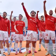 Piłkarze Wisły Kraków świętują, podnosząc ręce w geście triumfu. Ich stroje sugerują, że to ważny moment, być może związany z udanymi transferami.