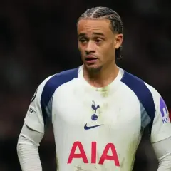 Jeden z tottenham zawodnicy w białej koszulce z granatowymi rękawami, z charakterystyczną fryzurą i skupionym wyrazem twarzy.