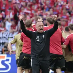 Trener Górnika Zabrze świętuje z drużyną. W tle kibice w barwach Górnika.