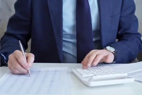 Biznesmen liczy zyski, analizując dokumenty i kalkulując podatek od zakładów bukmacherskich.