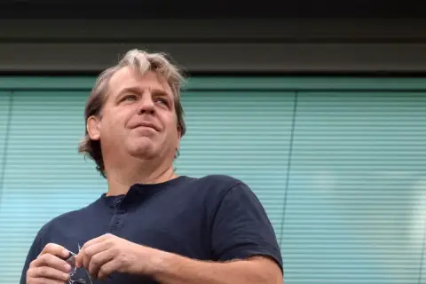 Todd Boehly, właściciel Chelsea, z okularami w dłoni, patrzy w górę z nadzieją.