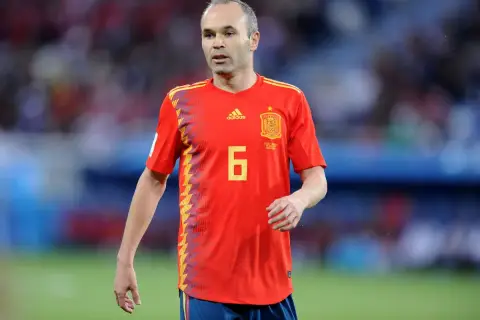 Hiszpański piłkarz Andres Iniesta w czerwonej koszulce z numerem 6 na boisku.
