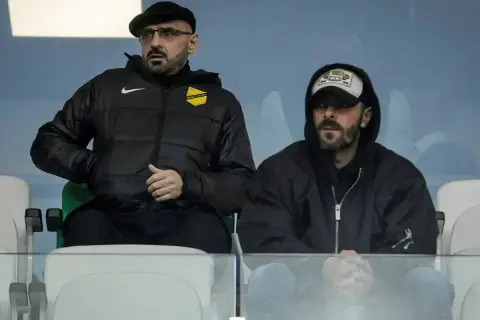 Dwóch mężczyzn siedzi na trybunach. Jeden z nich, w czapce i okularach, to właściciel wieczystej kraków.