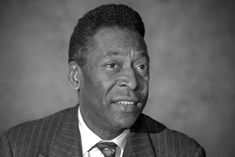 Portret czarno-biały. Uśmiechnięty mężczyzna w garniturze. Czy Pele żyje? Tak, legenda futbolu wciąż inspiruje.