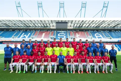 Piłkarze Wisły Kraków pozują do wspólnego zdjęcia na tle stadionu.