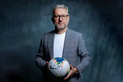 Jerzy Brzęczek, były selekcjoner kadry narodowej piłkarzy, trzyma piłkę nożną.