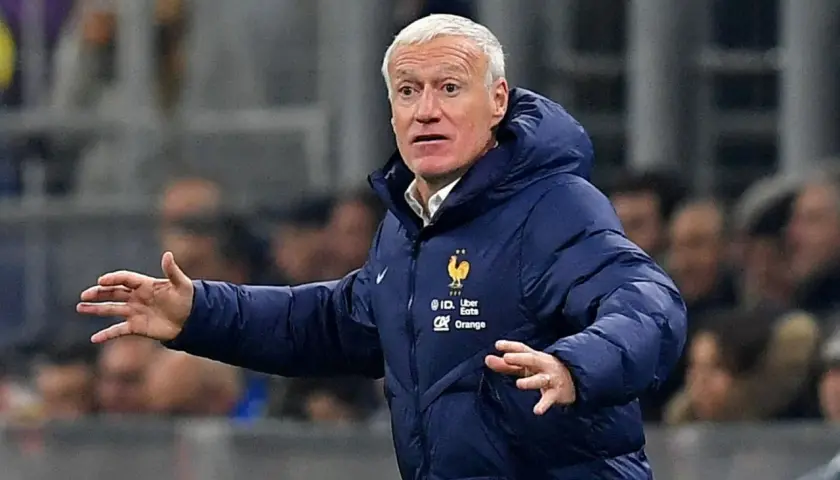 Didier Deschamps, trener Francji, w niebieskiej kurtce z herbem reprezentacji, gestykuluje na boisku.