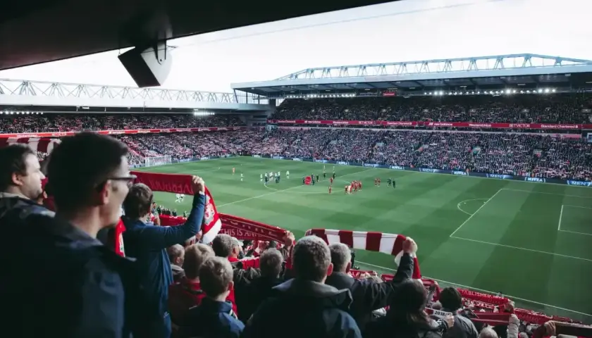 Kibice na stadionie z szalikami, czekają na wznowienie gry. Zastanawiają się, ile trwa przerwa w meczu.