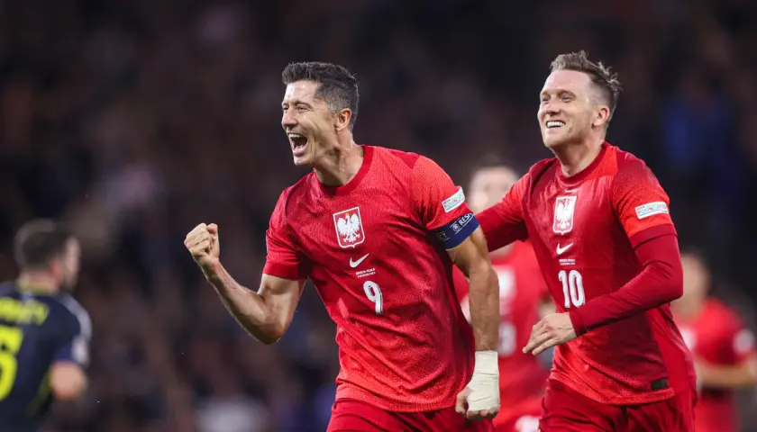 Piłkarze w czerwonych koszulkach świętują bramkę. Lewandowski z numerem 9 i jego kolega z numerem 10, duma klubu wybitnego reprezentanta.