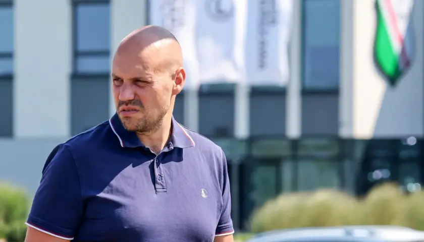 Łysy mężczyzna w granatowej koszulce polo, dyrektor sportowy Legii, patrzy w bok.
