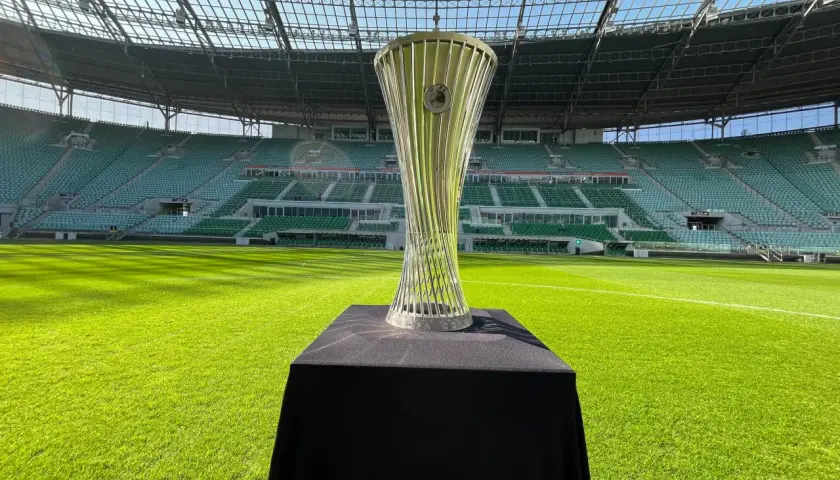 Trofeum Ligi Konferencji Europy UEFA błyszczy na tle pustego stadionu.