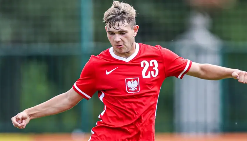 Piłkarz Rakowa w czerwonej koszulce z numerem 23 i godłem Polski, gotowy do gry w Lidze Europy.