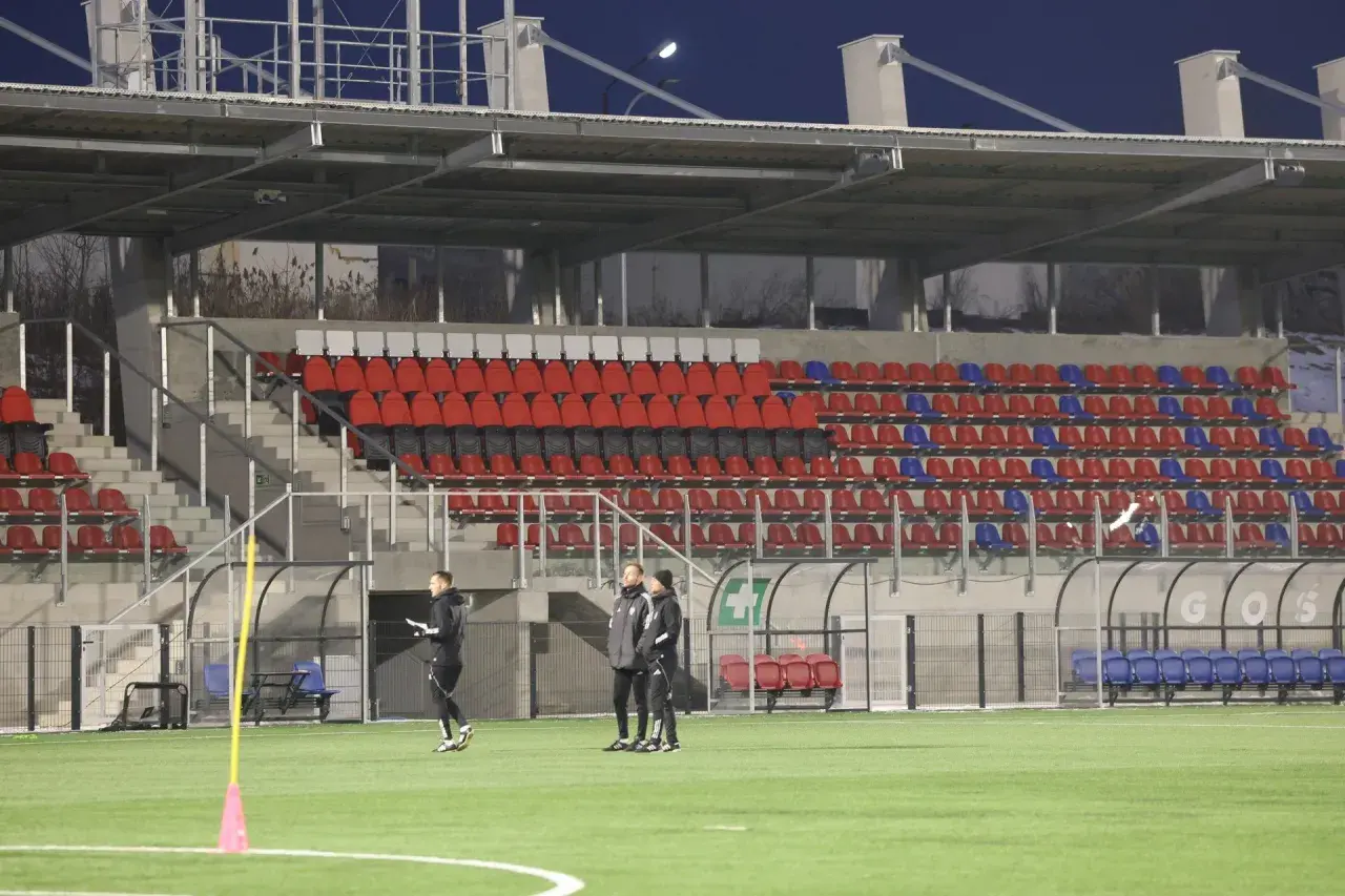 Piłkarze Polonii Bytom trenują na nowym stadionie. Puste trybuny z czerwonymi i niebieskimi krzesełkami czekają na kibiców.