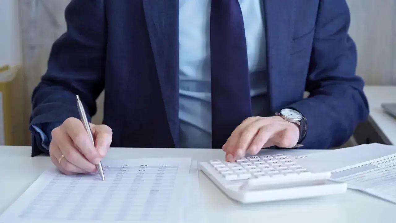 Biznesmen liczy zyski, analizując dokumenty i kalkulując podatek od zakładów bukmacherskich.