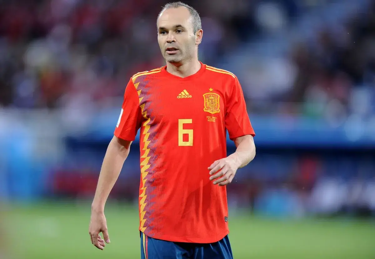 Hiszpański piłkarz Andres Iniesta w czerwonej koszulce z numerem 6 na boisku.
