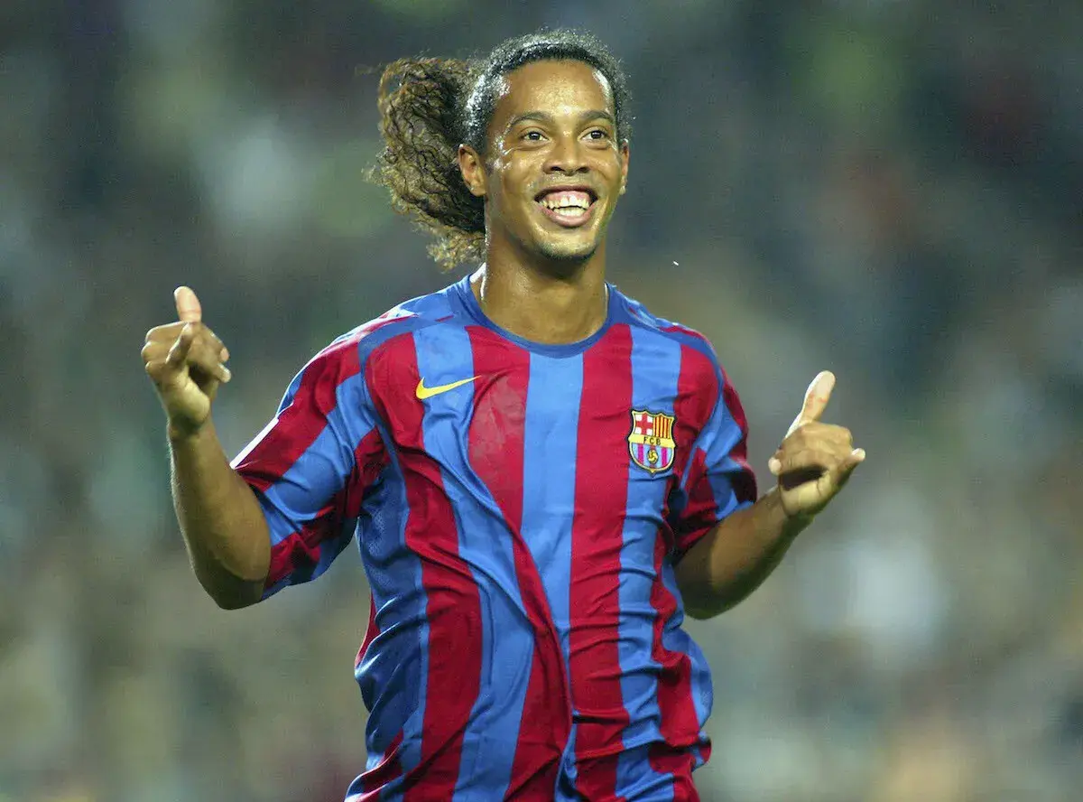 Ronaldinho w koszulce Barcelony, z charakterystycznym uśmiechem i uniesionymi kciukami, uosabia joga bonito.