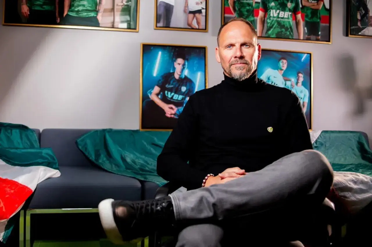 Trener Śląska Wrocław, Ivan Djurdjević, siedzi na kanapie w otoczeniu zdjęć piłkarzy.