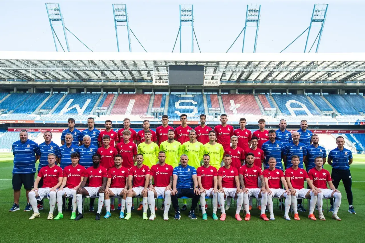 Piłkarze Wisły Kraków pozują do wspólnego zdjęcia na tle stadionu.