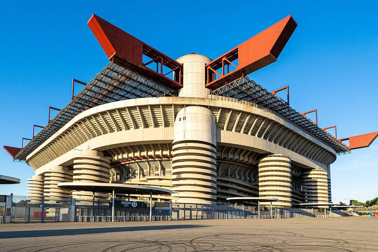 Imponujący mediolan stadion z charakterystycznymi czerwonymi elementami dachu i betonowymi kolumnami.