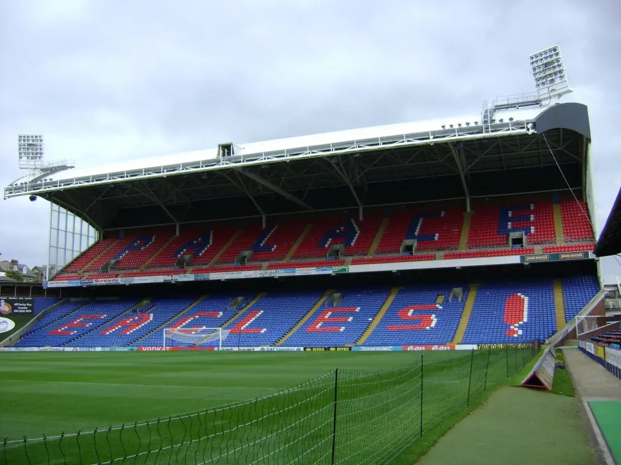 Trybuna stadionu Selhurst Park z czerwonymi i niebieskimi siedzeniami tworzącymi napisy.