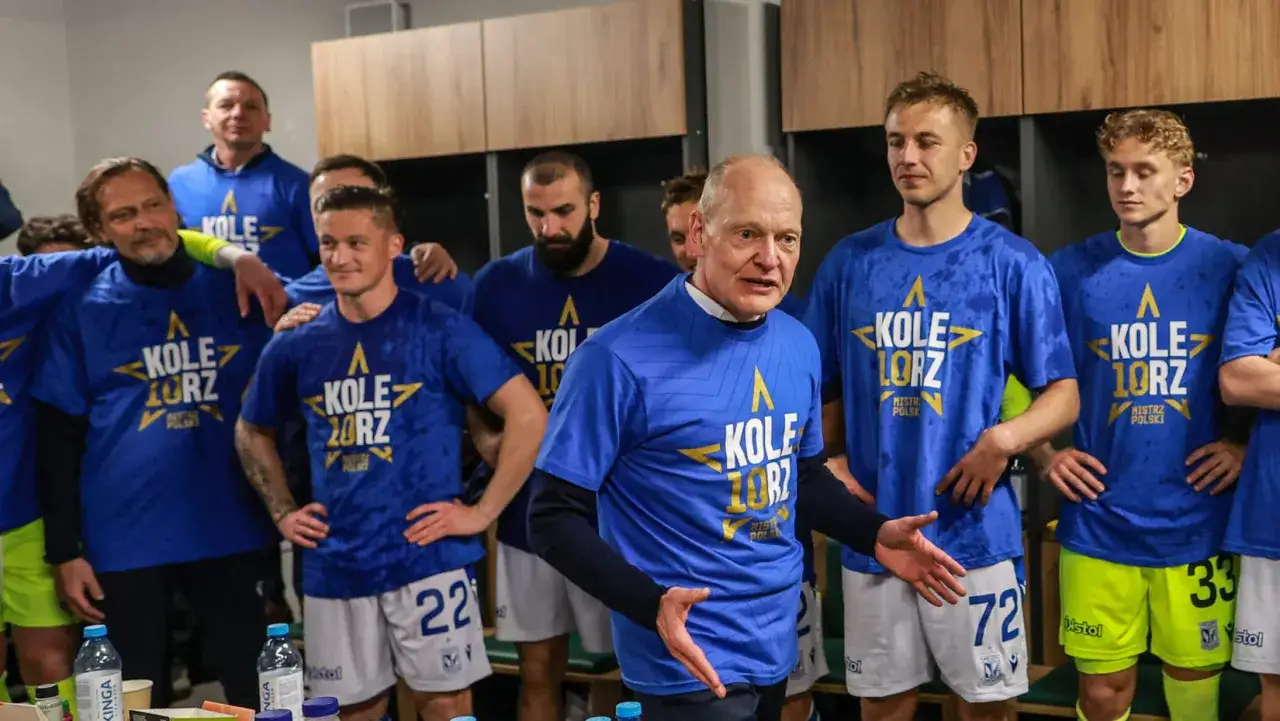 Trener Lecha w otoczeniu piłkarzy w niebieskich koszulkach z napisem 