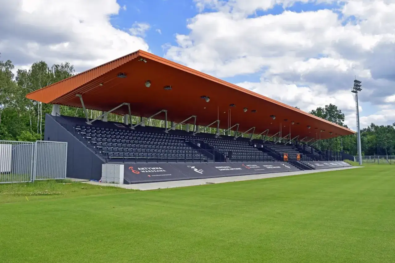 Trybuny stadionu z pomarańczowym zadaszeniem, idealne dla warszawskich klubów piłkarskich.