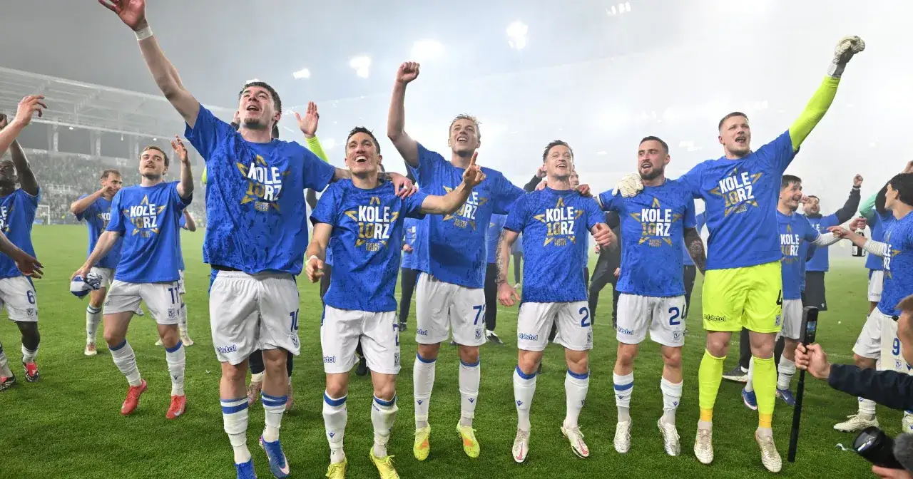 Piłkarze Lecha Poznań świętują zwycięstwo, wznosząc ręce w geście radości. Mają na sobie niebieskie koszulki z napisem