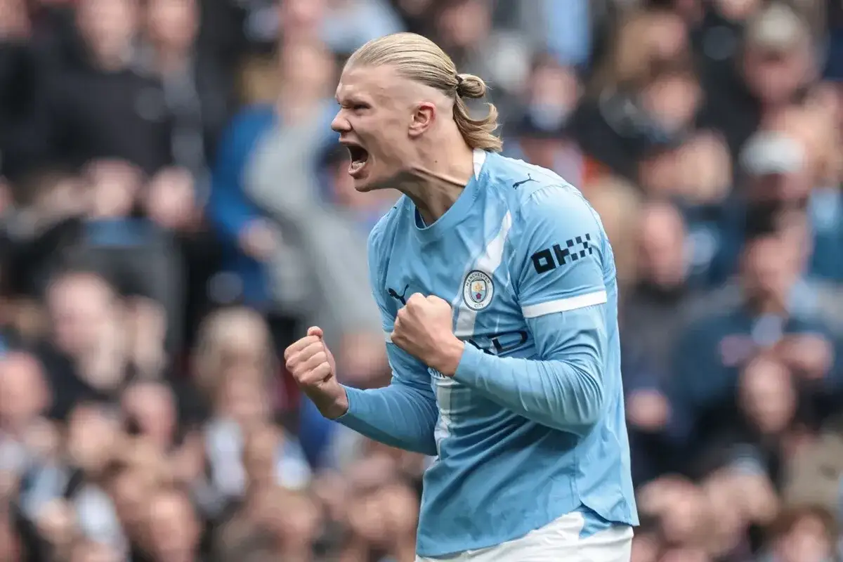Erling Haaland w błękitnej koszulce Manchesteru City, zaciśnięte pięści, radość po golu. Jego daty dołączenia do klubu są kluczowe dla sukcesów.