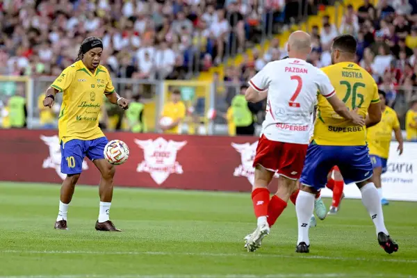 Ronaldinho w żółtej koszulce z numerem 10 drybluje piłką na boisku, gdzie grał.