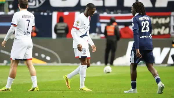 Piłkarz PSG, Ousmane Dembélé, schodzi z boiska, prawdopodobnie z powodu kontuzji. Obok niego inni zawodnicy.